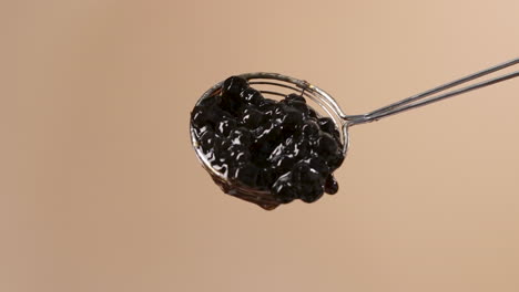 juicy black tapioca pearls slowly falling from round spider strainer