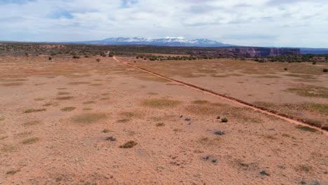 Moving-drone-shot-over-the-desert-with-a-off-road-trail-and-van-in-view