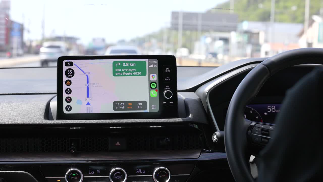 Interior car view with GPS navigation on screen, driving through Phuket. Bright daylight, clear dashboard, and road ahead visible
