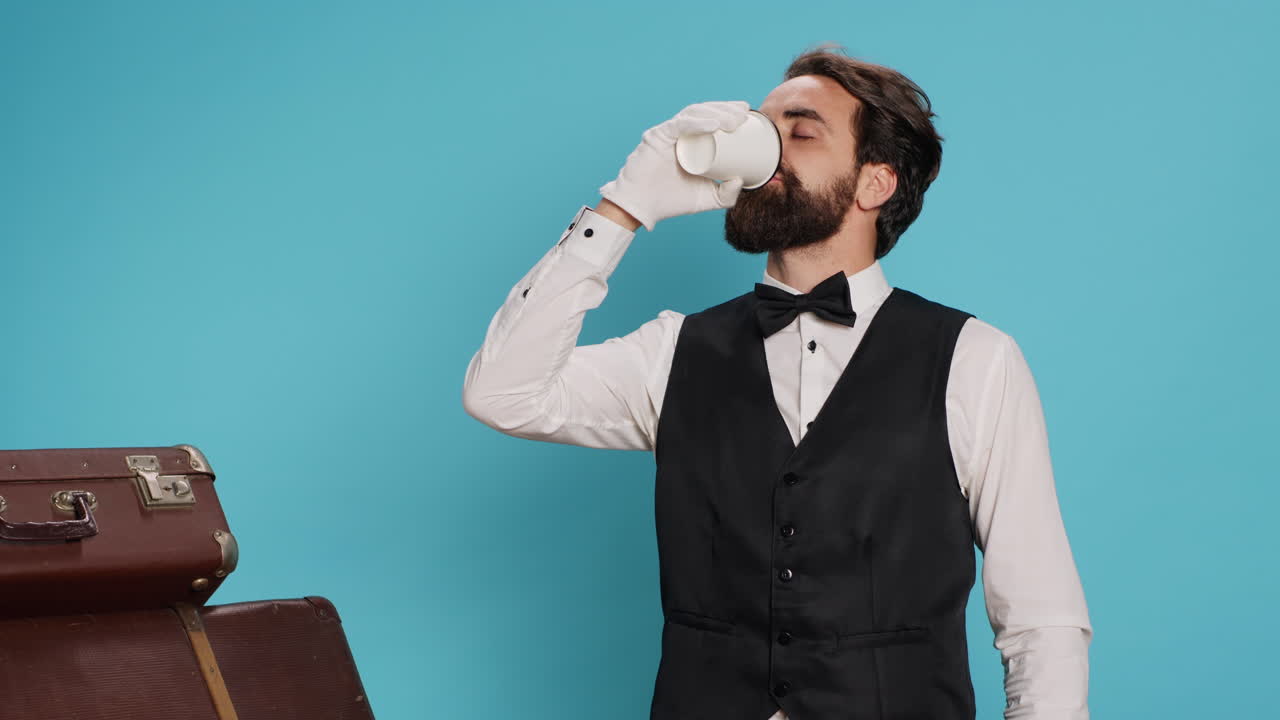 el portero del hotel bebiendo café ante la cámara.