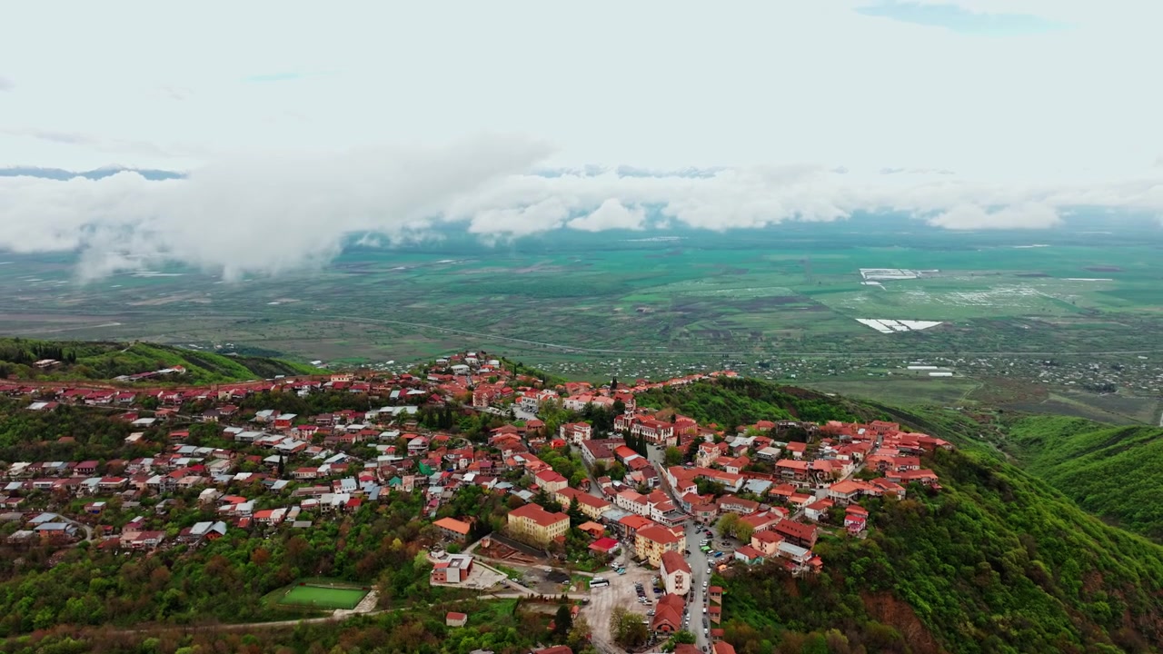 Ripresa aerea elevata della città di Sighnaghi che domina vigneti, valli e orizzonti pacifici della campagna georgiana