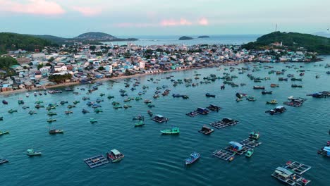 drone shot of phu quoc island during sunset. a fishing village with numerous fishing boats in the water and a cable car station visible on the horizon. vietnam
