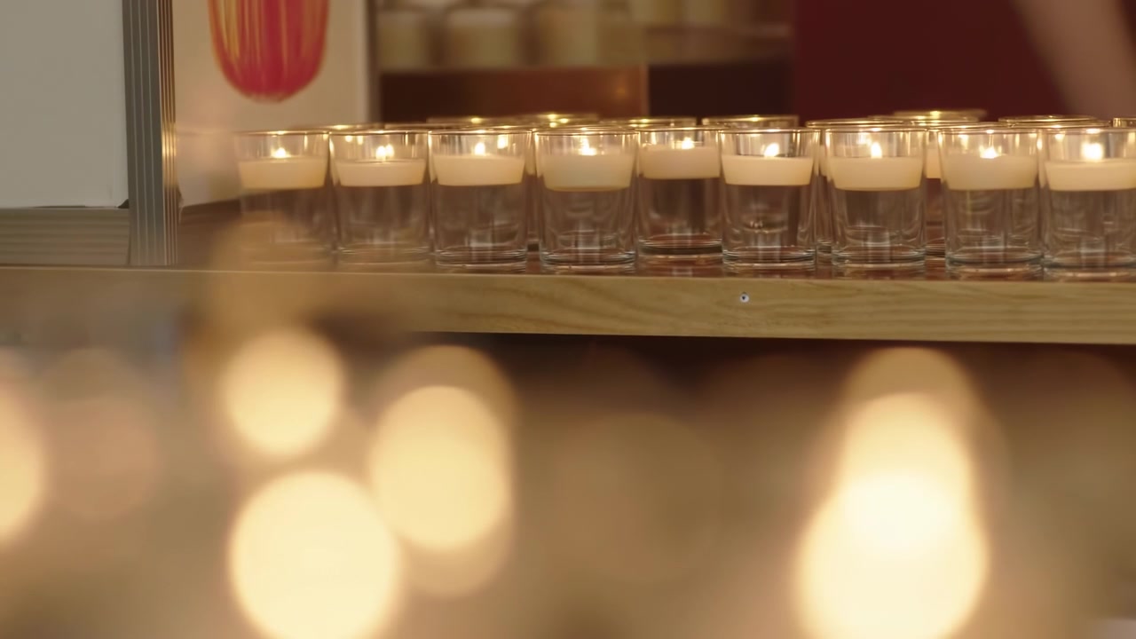 Små ljushållare i glas kantar en trähylla medan stora gyllene bokeh-cirklar glöder i suddig förgrund, vilket skapar en mysig elegant interiöratmosfär med mjukt bärnstensfärgat ljus, mjukt djup och lugn stämning.