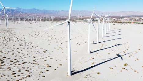muchos molinos de viento giran en una zona desértica caliente, los drones vuelan hacia atrás