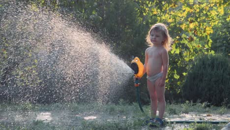 child playing with water hose in garden