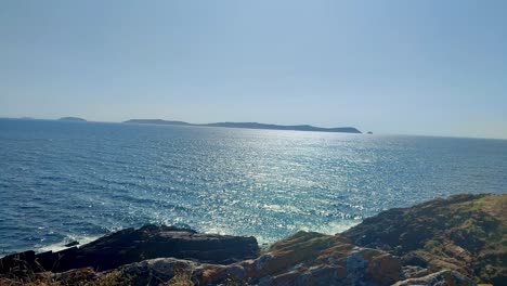 Schwenkaufnahmen-Des-Außergewöhnlich-Blauen-Ozeans-Vom-Klippenland-Und-Der-Insel-Am-Horizont