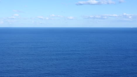 panoramic view of serene blue ocean under clear sky with clouds