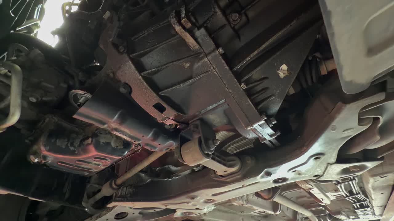 Undercarriage view of a red car elevated on a hydraulic scissor lift ...