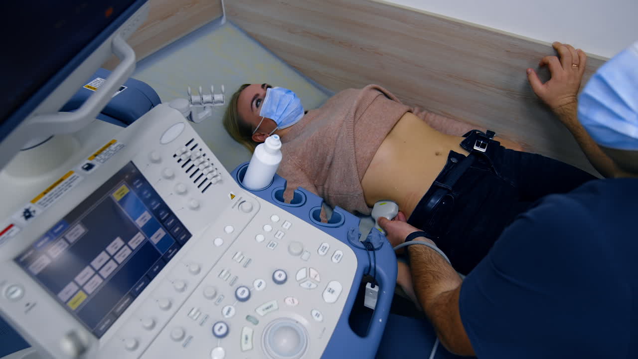 Male obstetrician applies ultrasound device to a woman's side. Doctor examines patient's kidneys. Top view.