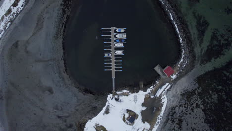 toma aérea con plataforma rodante del puerto de ase mirando hacia los barcos, el muelle y el rompeolas con nieve ligera y aguas negras