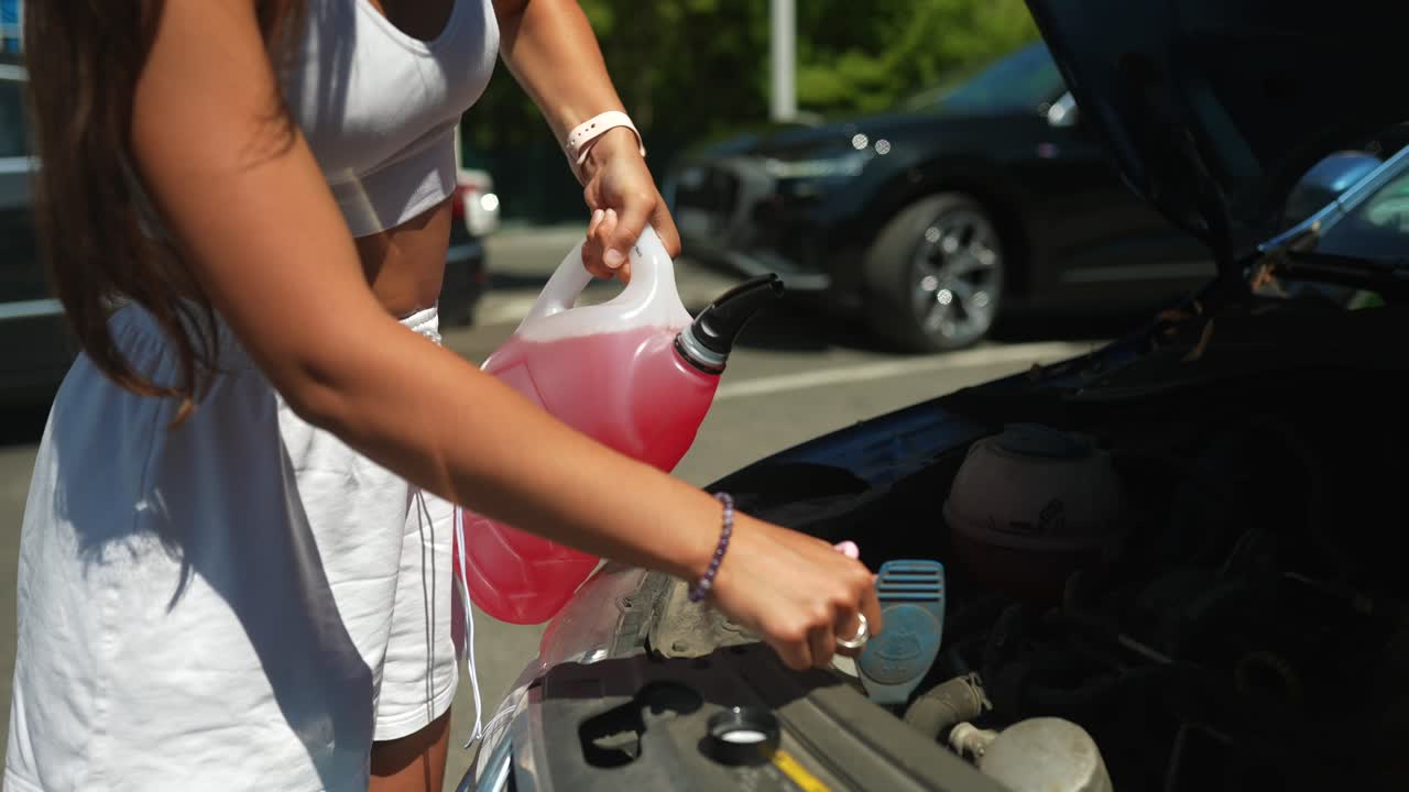 여성이 자동차 라디에이터 액체를 채우고 있습니다.
