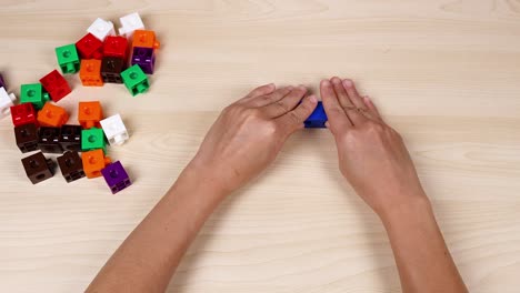 hands assembling cubes on a wooden table