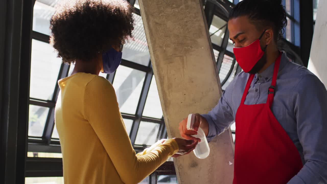 trabajador de café de raza mixta que usa una máscara facial tomando la temperatura de una compañera de trabajo