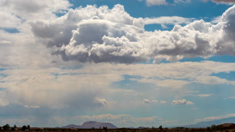 a dynamic cloudscape with abstract shapes forms above the desert landscape - daytime time lapse