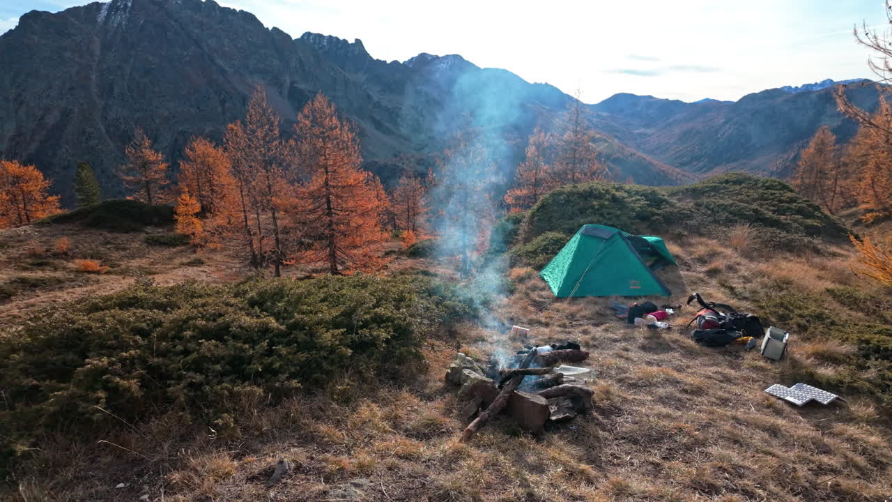 Mountain campsite with tent and campfire in autumn forest
