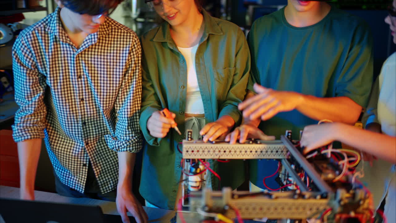 Young engineers with VR virtual reality headset fixing a robotic car in research laboratory, slow motion