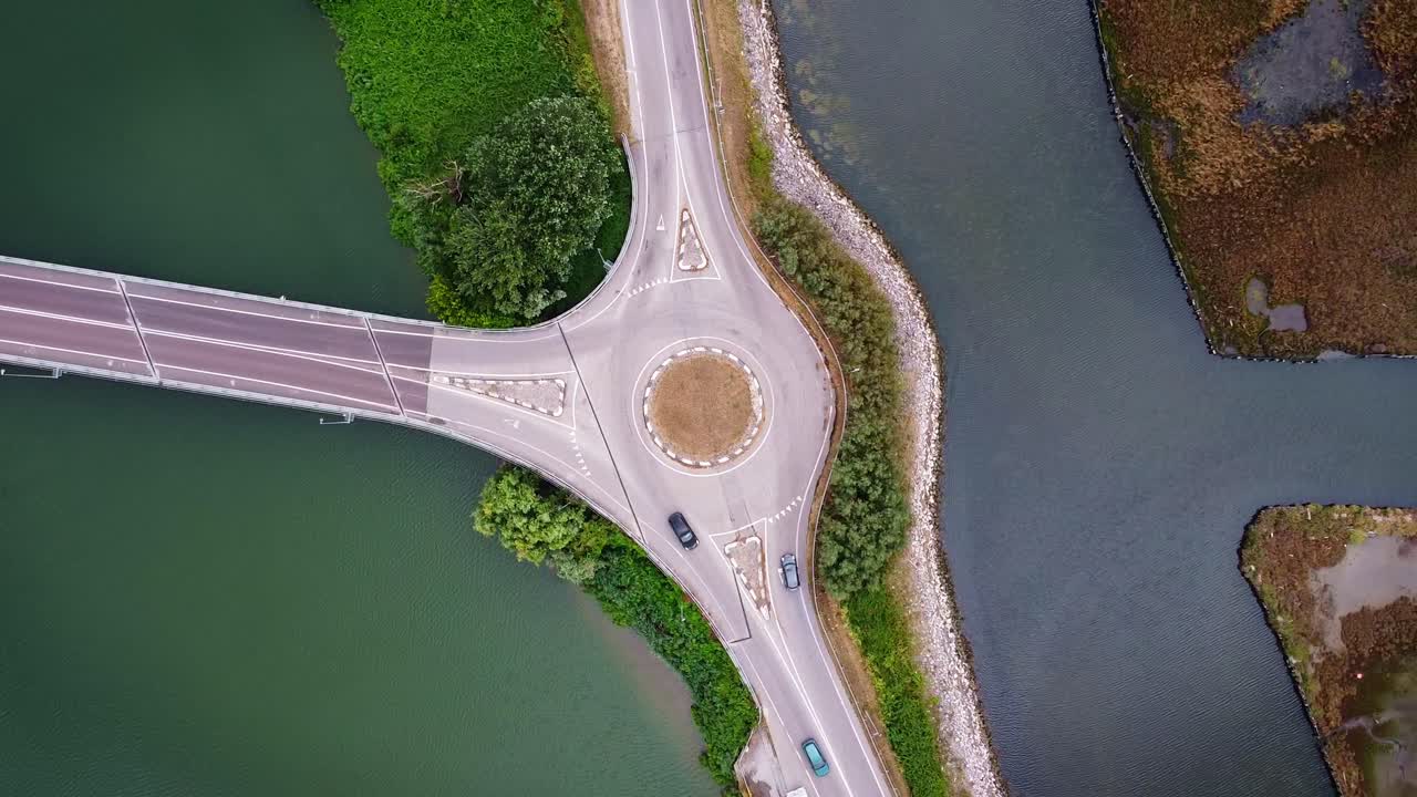 Aerial drone view of roundabout surrounded by water canals and greenery in Marina di Ravenna, Italy, scenic traffic flow and road patterns from above