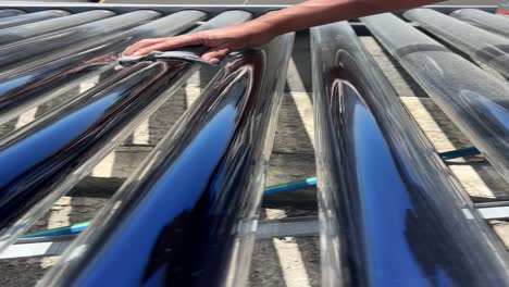 close up of a man cleaning vacuum solar water heating system on the house roof