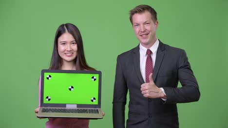 young asian woman and young businessman showing laptop together