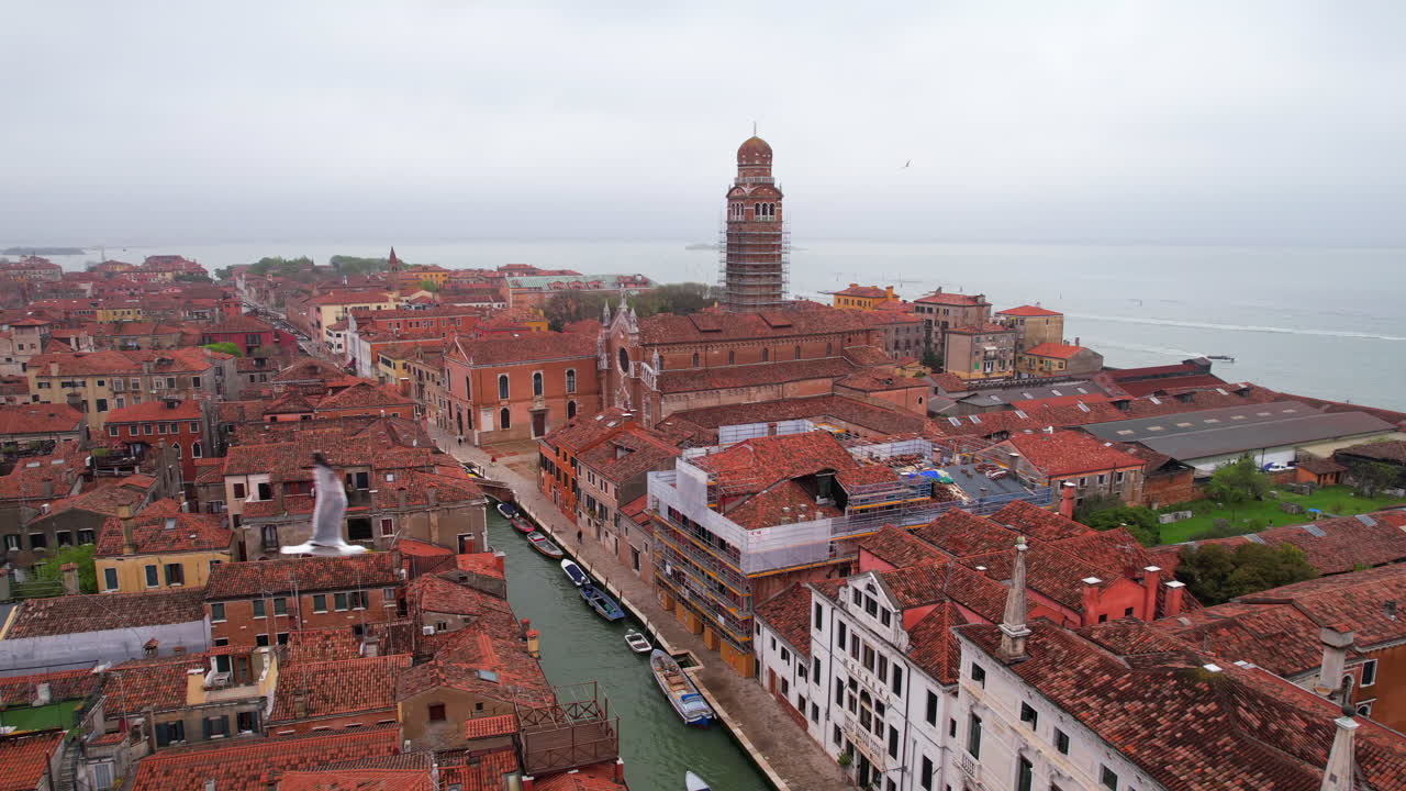 Venetian tower under construction work while seagulls fly. Aerial