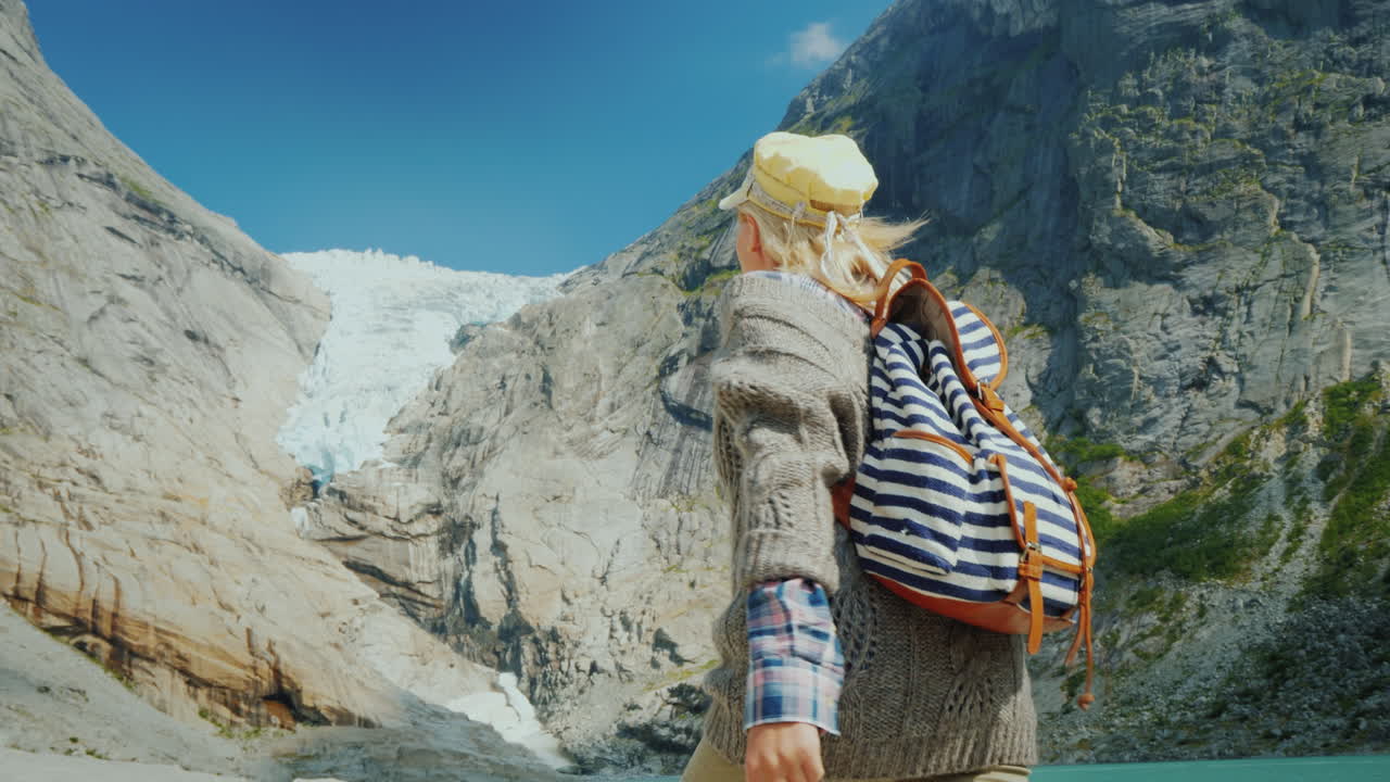 A Woman In Warm Clothes Admires The Glacier High In The Mountains Briksdal Glacier In Norway A Trip 