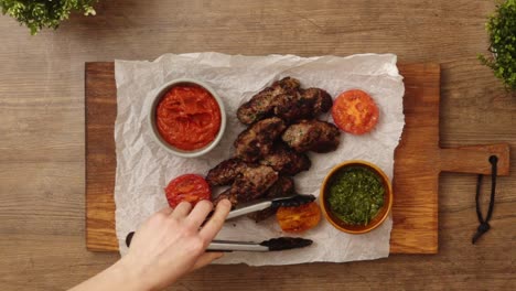 persona anónima que sirve tomates a la parrilla cerca de salisbury filetes con salsas