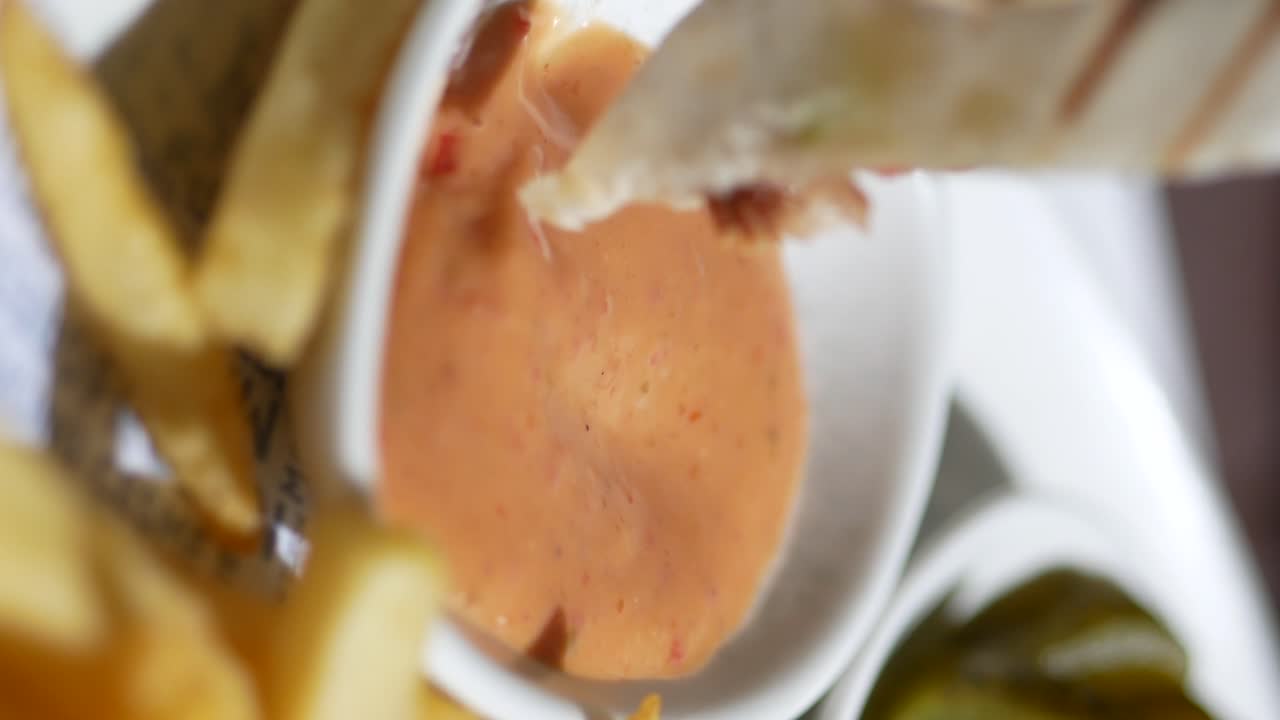 Dipping a wrap in sauce with french fries