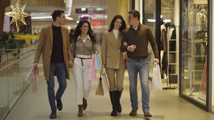 Two happy couples enjoy a day of shopping together at a modern mall, carrying their purchases