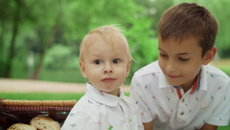 adorable niño mirando lejos en el parque. niño amigable abrazando a su hermano afuera