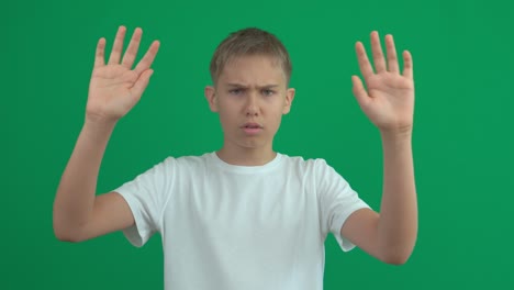 denying, rejecting, disagree, disapproving. teenage boy says no with crossed hands, stop gesture making negation sign over green screen chroma key background