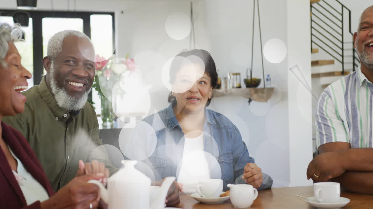 Drikker te sammen, smilende venner med ulik bakgrunn, med animasjon av lys bokeh-effekt