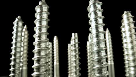 close-up of multiple silver screws standing upright against a dark background