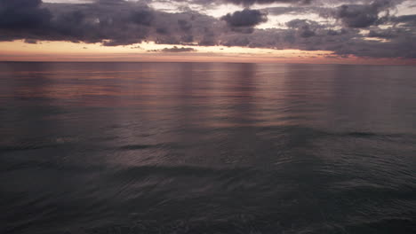 Aerial-drone-establishing-shot-of-a-sunset-as-calm-ocean-waves-roll-into-a-white-sand-beach-in-Cancun,-Mexico