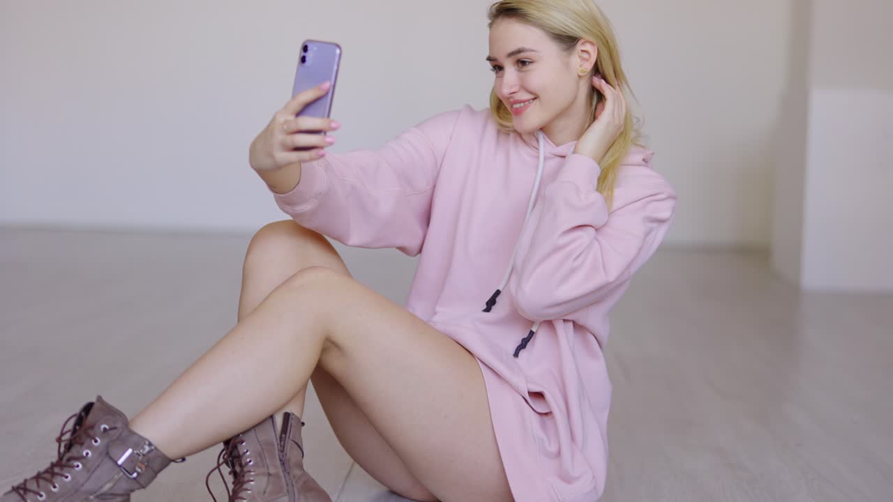 una mujer tomando una selfie con una sudadera rosa