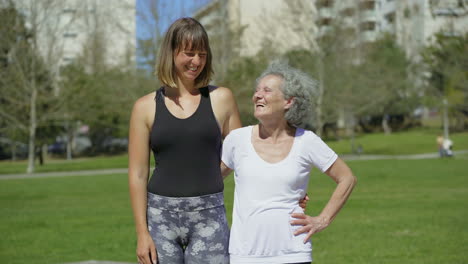 smiling young woman hugging senior lady in park.