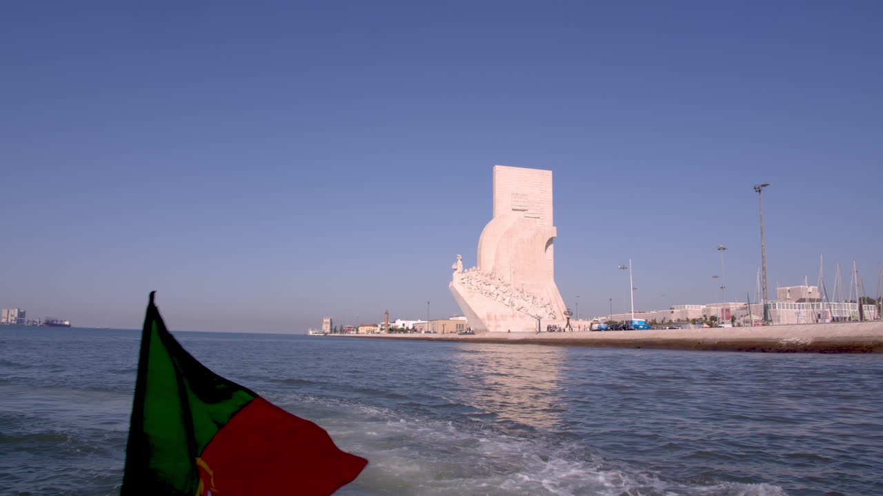 Padrão dos descobrimentos monument tracking shot by boat.at sunrise. Portuguese flag on the shot. Slow motion