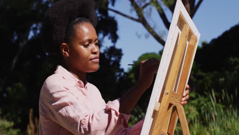 Mujer-Afroamericana-Pintando-Un-Cuadro-Sobre-Lienzo-En-Un-Jardín-Soleado