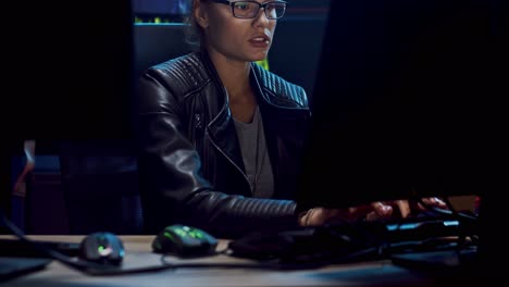 attractive female software developer in glasses working over the hacking programs at the dark room, then leaning on the chair and resting from tensive job