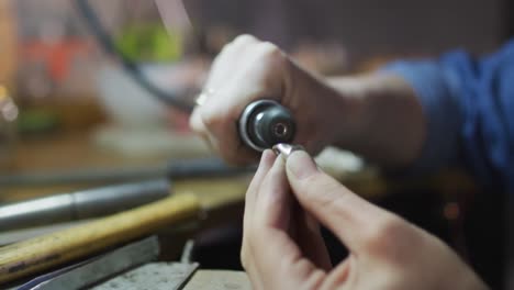 close up of hands of caucasian female jeweller using tools, making jewelry