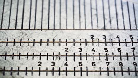 Camera slides from top to bottom to reveal close up footage of golf equipment measuring device showing words, numbers and black increment marks-lines