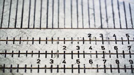 camera slides from top to bottom to reveal close up footage of golf equipment measuring device showing words, numbers and black increment marks-lines