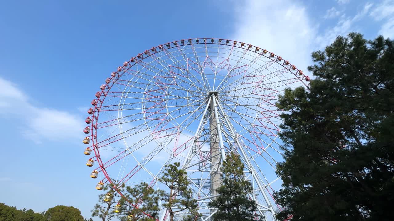 Ferris wheel in a theme park with a clear blue sky above, shot in Tokyo, Japan