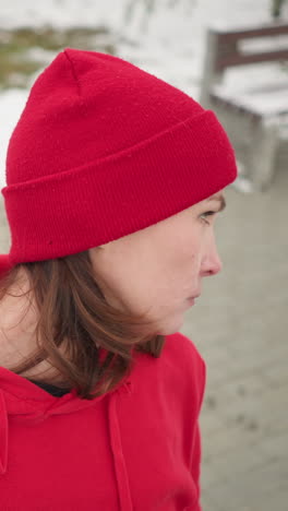 woman turns head from right to left slowly with eyes closed, focusing inward in calm meditative state, snowy background features benches and frosted trees in serene atmosphere
