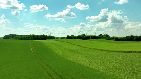 Luftaufnahme-Von-Grünen-Feldern-Mit-Windrädern,-Strahlend-Blauem-Himmel-Und-Vereinzelten-Wolken---Vorwärts