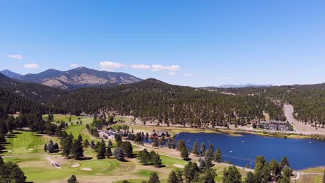 view of golf carts on golf course and kayaks on lake in the mountains on sunny day