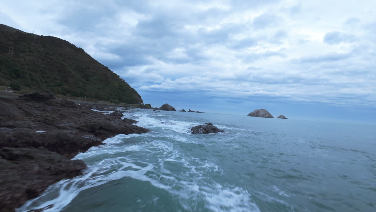 FPV drone shot of the rocky coast of Goosebay, gloomy evening in New Zealand