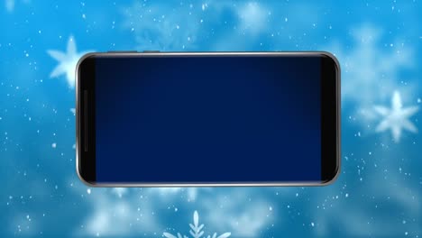 Animación-De-La-Pantalla-Del-Teléfono-Inteligente-En-Blanco-Con-Paisajes-Invernales-Y-Nieve-Cayendo-Sobre-Fondo-Azul