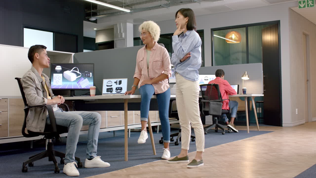 Discussing project, diverse team collaborating with computer screens in modern office