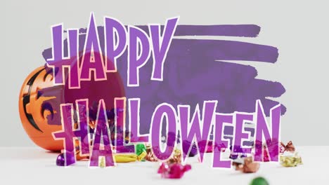 Animation-of-happy-halloween-text-over-pumpkin-bucket-with-sweets
