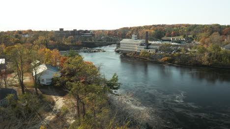 Fliegen-In-Richtung-Historisches-Mühlengebäude-Am-Ufer-Eines-Flusses-Im-Herbst,-Brunwick,-Maine